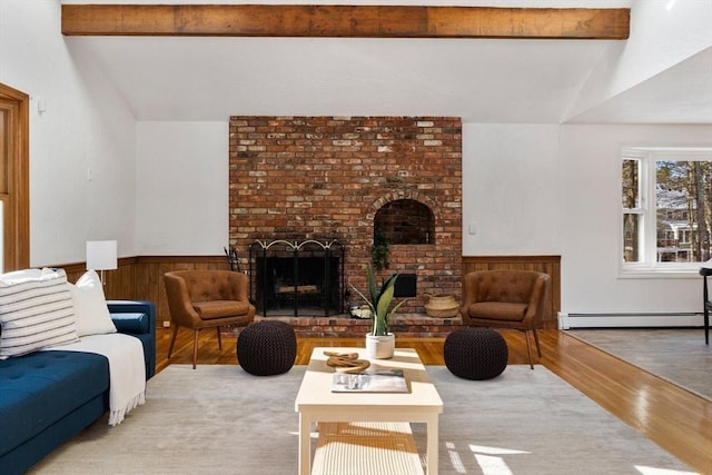 living room with a baseboard radiator, a brick fireplace, vaulted ceiling with beams, and light hardwood / wood-style flooring