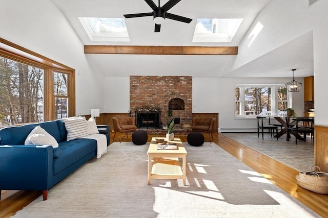 living room with a brick fireplace, ceiling fan with notable chandelier, plenty of natural light, and lofted ceiling with skylight