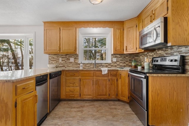 kitchen with backsplash, a wealth of natural light, stainless steel appliances, and kitchen peninsula