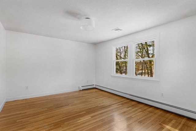 unfurnished room with a baseboard heating unit and wood-type flooring