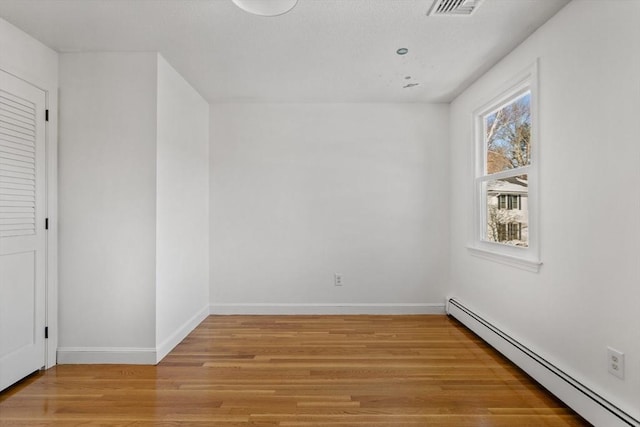 unfurnished room featuring baseboard heating and light hardwood / wood-style flooring