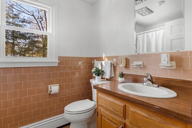 bathroom with vanity, toilet, tile walls, and a baseboard heating unit