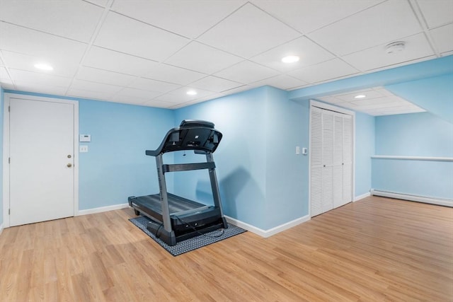 workout area with baseboard heating and light hardwood / wood-style floors