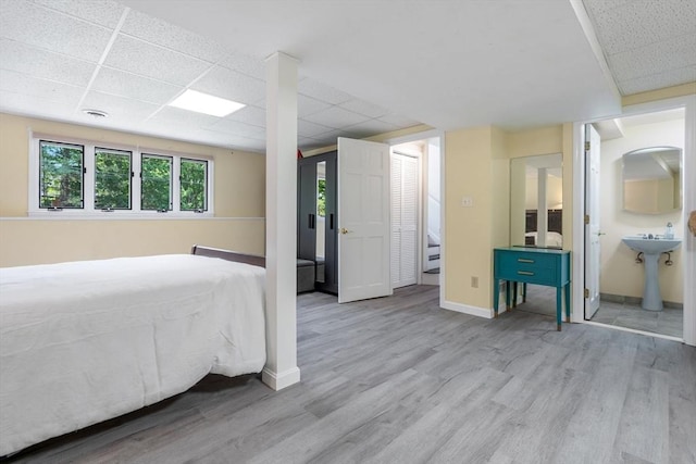 unfurnished bedroom featuring a paneled ceiling, ensuite bath, and light hardwood / wood-style flooring