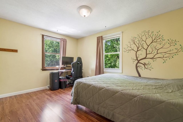 bedroom featuring multiple windows, hardwood / wood-style floors, and a textured ceiling