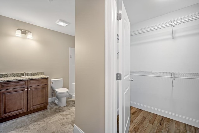 full bath featuring a walk in closet, baseboards, and toilet