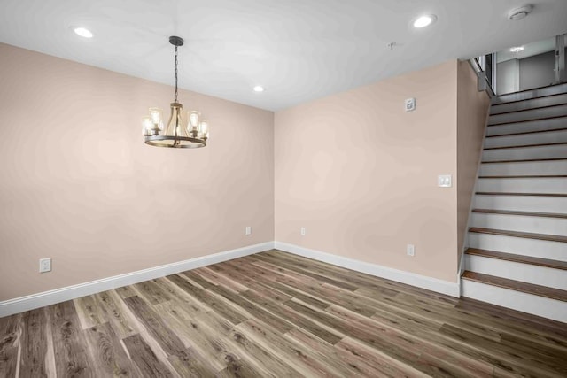 unfurnished room with baseboards, a chandelier, recessed lighting, wood finished floors, and stairs