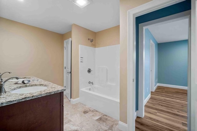 bathroom featuring double vanity, baseboards, a sink, and shower / washtub combination