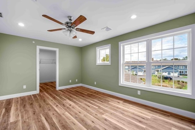 unfurnished bedroom with baseboards, a spacious closet, recessed lighting, light wood-style floors, and visible vents
