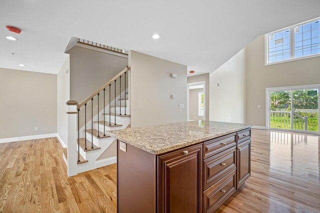 kitchen with a wealth of natural light, baseboards, light wood-style floors, and light stone countertops