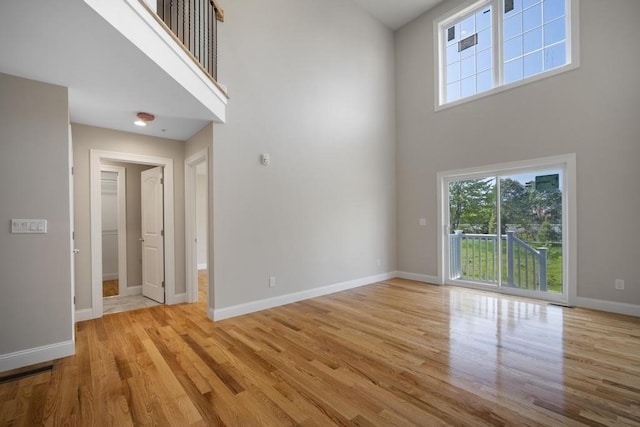 interior space featuring a towering ceiling, baseboards, and wood finished floors