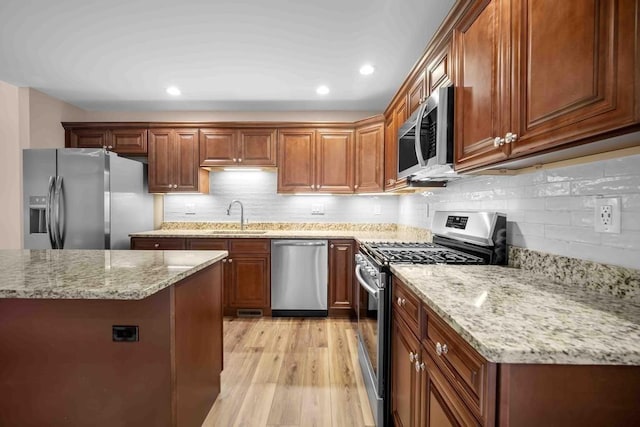 kitchen with light stone counters, recessed lighting, appliances with stainless steel finishes, light wood finished floors, and a sink