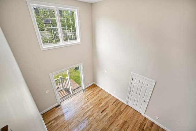 interior space featuring a towering ceiling, light wood-style flooring, and baseboards