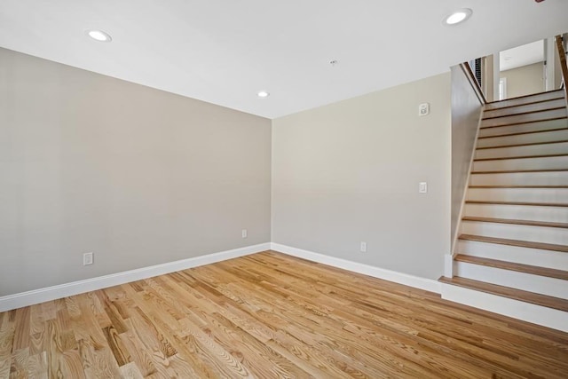 empty room featuring light wood-type flooring, recessed lighting, baseboards, and stairs