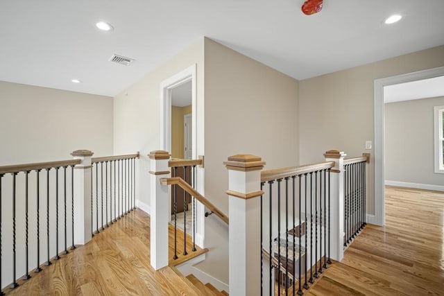 hallway featuring baseboards, recessed lighting, an upstairs landing, visible vents, and wood finished floors