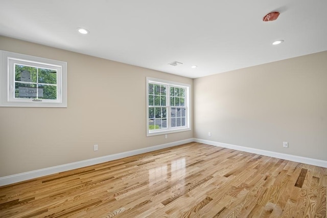empty room featuring light wood-style flooring, baseboards, visible vents, and recessed lighting