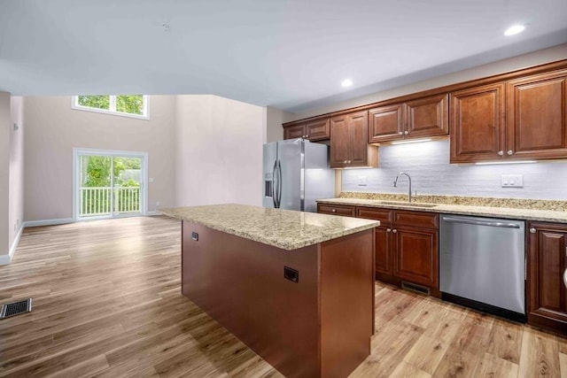 kitchen featuring light wood-style flooring, a kitchen island, visible vents, stainless steel appliances, and a sink