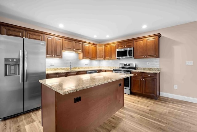 kitchen featuring light stone countertops, a sink, stainless steel appliances, decorative backsplash, and baseboards