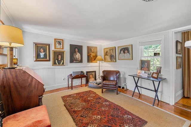 163/165 Highland St, Dedham, MA 02026 - sitting room featuring wood finished floors, a wainscoted wall, and radiator heating unit
