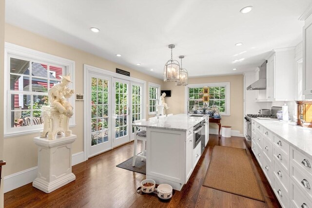 163/165 Highland St, Dedham, MA 02026 - kitchen with wall chimney exhaust hood, appliances with stainless steel finishes, white cabinetry, a kitchen island, and dark wood-type flooring