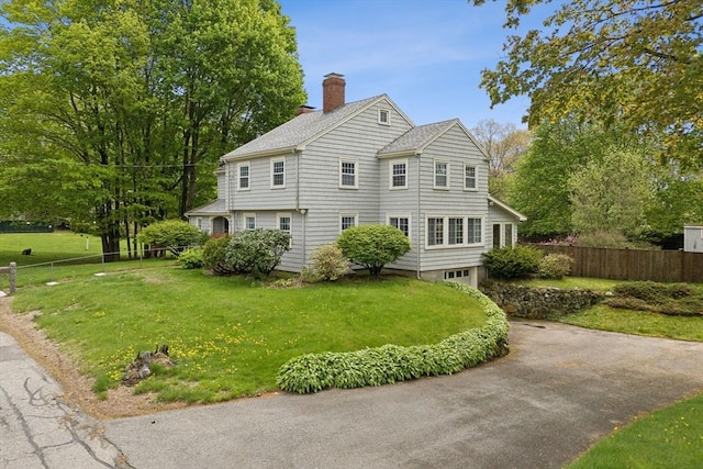 view of property exterior with a chimney, an attached garage, driveway, and a shingled roof