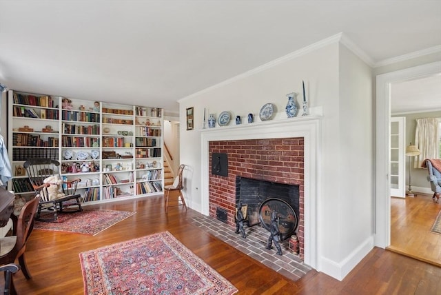 living area with crown molding, wood finished floors, a fireplace, baseboards, and stairway