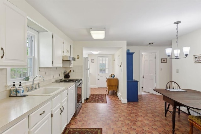 kitchen featuring gas range, freestanding refrigerator, under cabinet range hood, a sink, and white cabinets