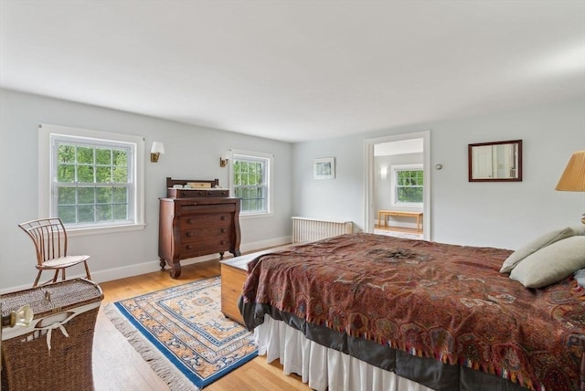 bedroom featuring light wood-style floors, radiator heating unit, and baseboards