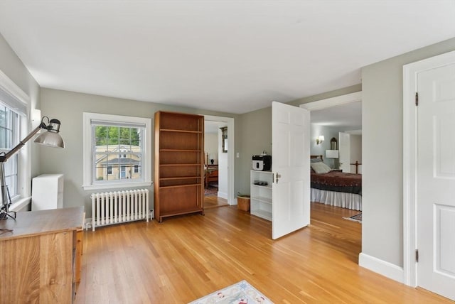 living area featuring radiator, light wood-style flooring, and baseboards