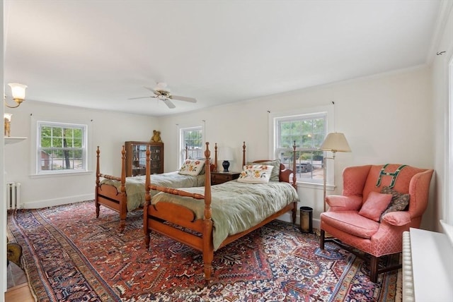 bedroom with radiator heating unit, baseboards, ceiling fan, wood finished floors, and ornamental molding