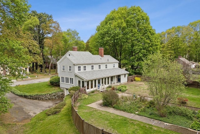 back of house featuring a chimney and a shingled roof