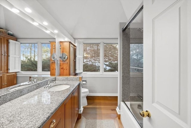 bathroom with baseboards, toilet, wood finished floors, vaulted ceiling, and vanity