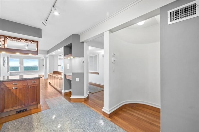 interior space featuring visible vents, baseboards, brown cabinets, ornate columns, and granite finish floor