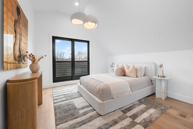 bedroom with vaulted ceiling, access to exterior, and light wood-type flooring