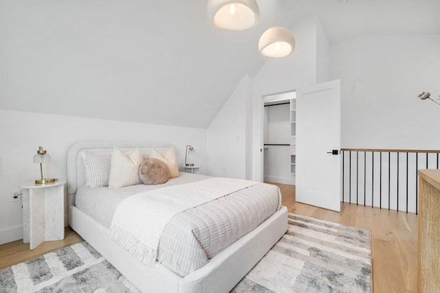 bedroom featuring lofted ceiling, a spacious closet, wood-type flooring, and a closet