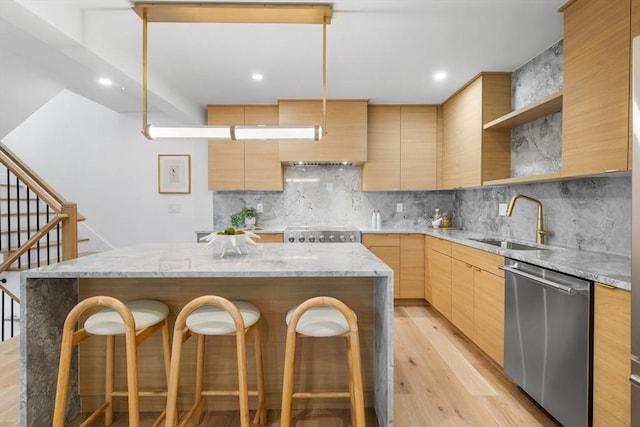 kitchen with sink, light stone countertops, a center island, and dishwasher