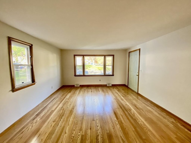 unfurnished room with light wood-style flooring, plenty of natural light, and baseboards