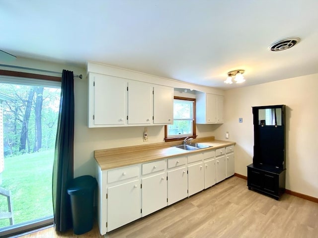 kitchen featuring a sink, light wood-style flooring, white cabinetry, and light countertops