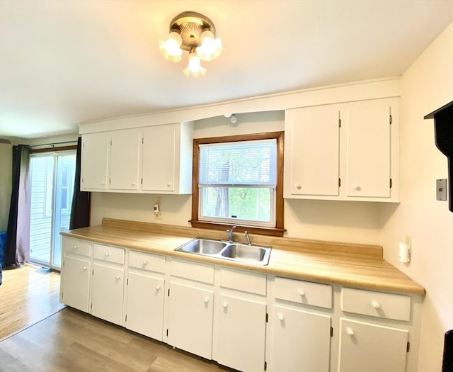 kitchen featuring a sink, light wood-style floors, white cabinetry, and light countertops