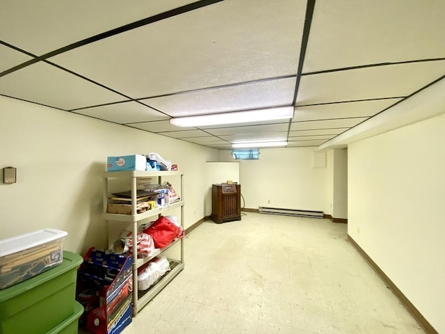 finished basement with baseboards, tile patterned floors, baseboard heating, and a drop ceiling