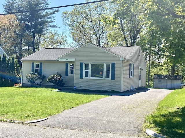 view of front of property with driveway, an outdoor structure, a front yard, and roof with shingles
