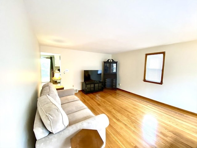 living room with light wood-style flooring, healthy amount of natural light, and baseboards