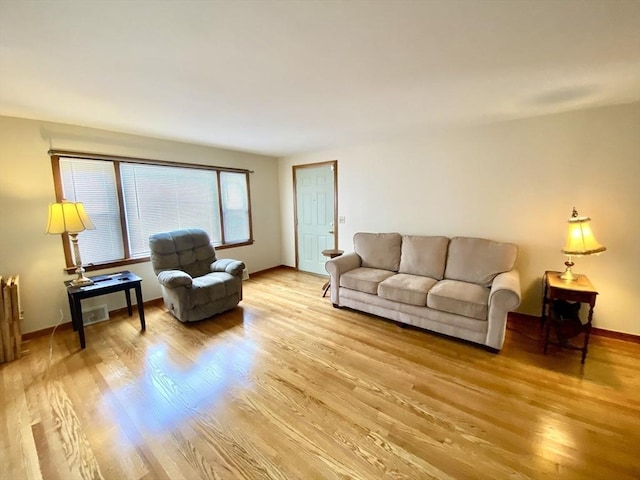 living room featuring light wood-style floors, baseboards, and radiator