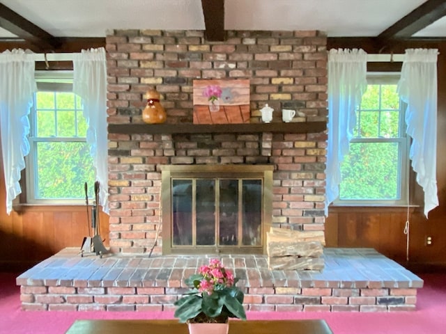 room details featuring carpet floors, wood walls, beam ceiling, and a brick fireplace