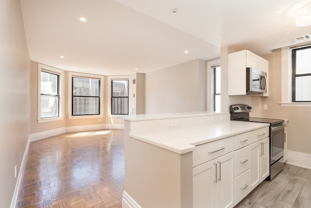 kitchen with white cabinets, kitchen peninsula, appliances with stainless steel finishes, and plenty of natural light