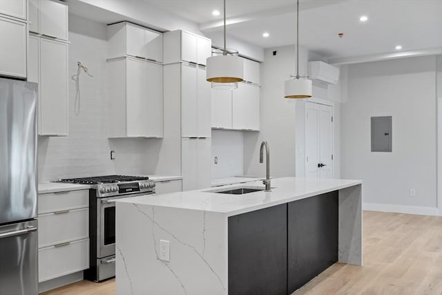 kitchen featuring stainless steel appliances, sink, white cabinetry, a center island with sink, and pendant lighting