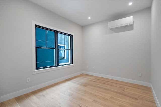 unfurnished room with light hardwood / wood-style floors and an AC wall unit