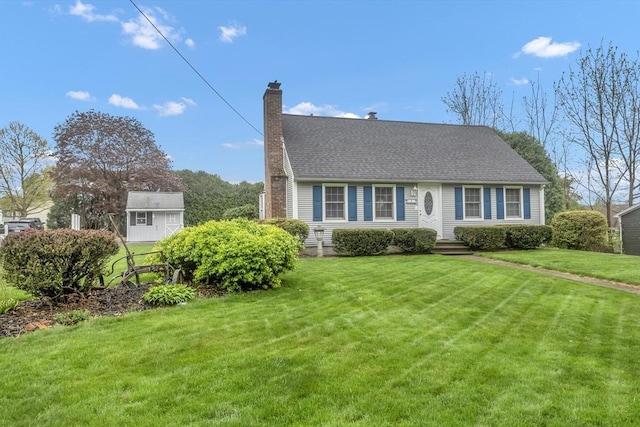 cape cod house with a chimney, a front lawn, and an outdoor structure