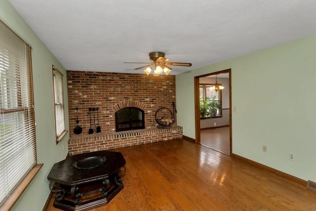 unfurnished living room featuring ceiling fan, wood finished floors, a fireplace, baseboards, and a textured ceiling