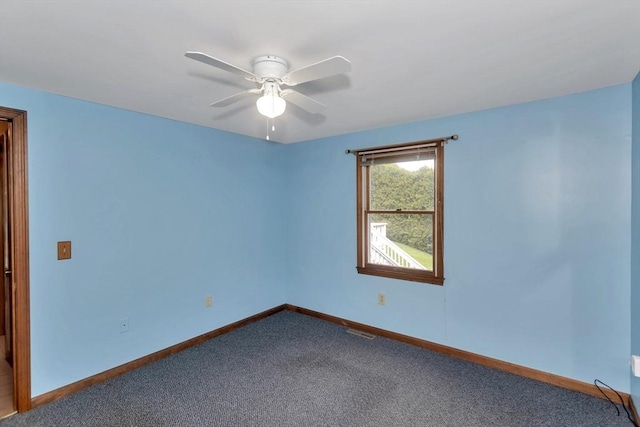 empty room with dark carpet, a ceiling fan, and baseboards